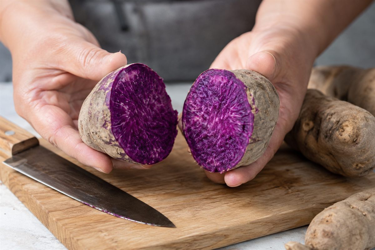Ube kinampay coupé en deux à la main, chair violette profonde et marbrée