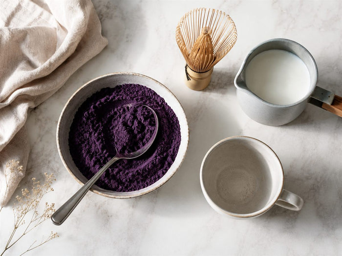 Préparation d'un ube latte : bol de poudre d'ube, fouet, lait et tasse