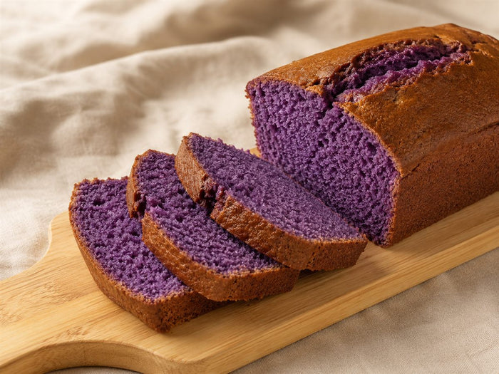 Cake a l'ube tranche, mie violette moelleuse, croute doree, planche bois, fond lin