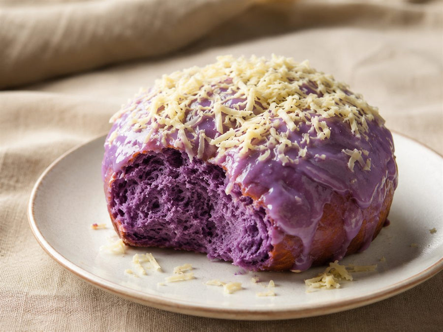 Brioche ensaymada a l'ube violette, glacage et fromage rape, assiette claire, fond lin