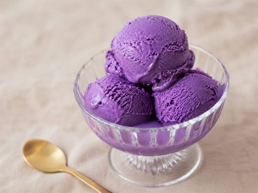 Boules de glace a l'ube violettes dans une coupe en verre, cuillere doree, fond lin