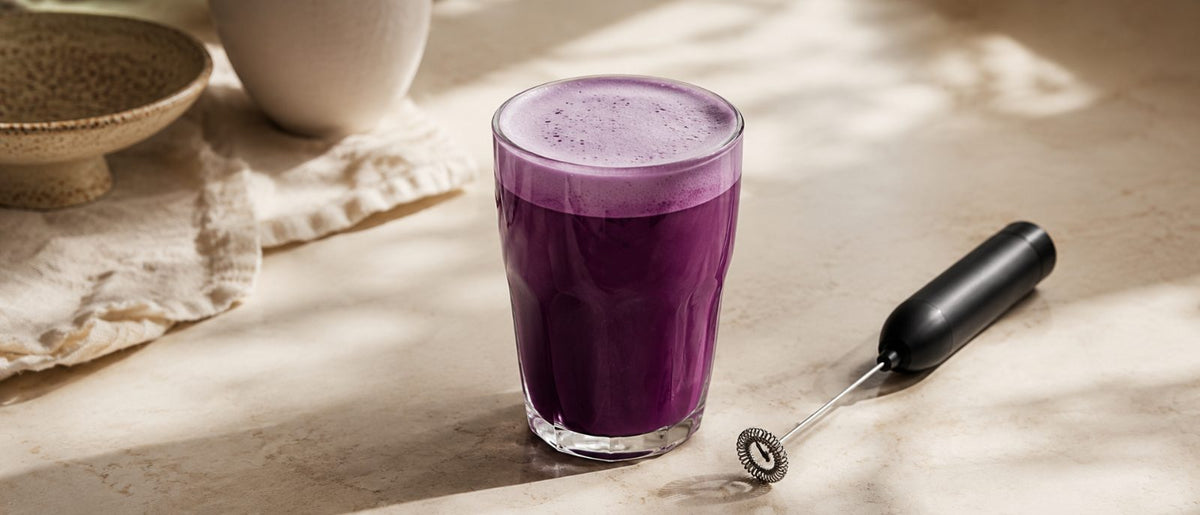 Ube latte violet préparé au mousseur à lait, mousse onctueuse, plan de travail crème