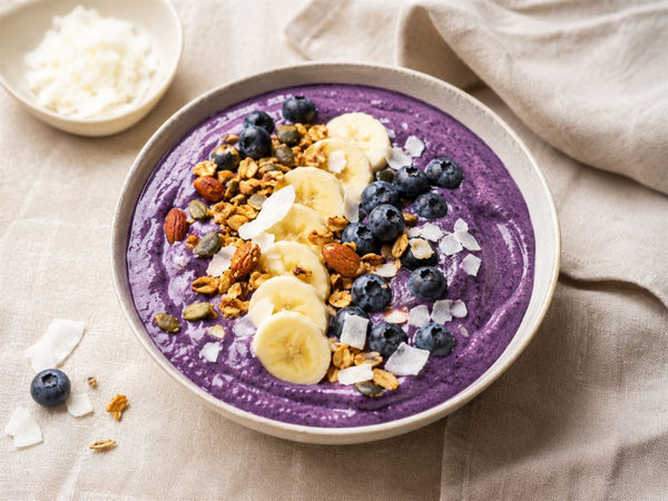 Smoothie bowl a l'ube violet, granola banane myrtilles coco, bol clair, fond lin