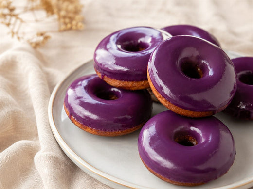 Donuts a l'ube glaces violet brillant, sur assiette claire, fond lin beige