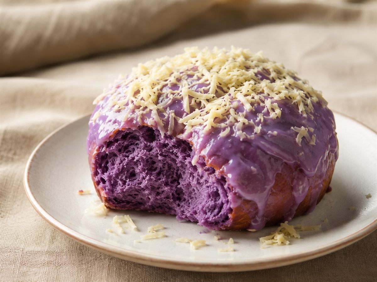 Brioche ensaymada a l'ube violette, glacage et fromage rape, assiette claire, fond lin