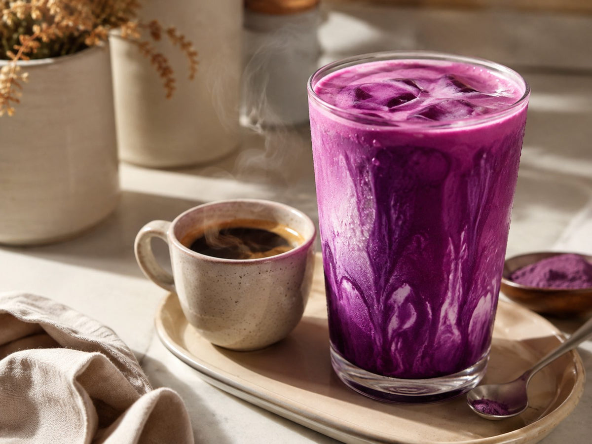 Verre d'ube latte violet foncé à côté d'une tasse d'espresso, association ube et café